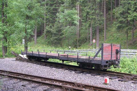 Vom ehemaligen GGw ist an dem Flachwagen nur noch ein Teil der Stirnwand mit dem Handbremsrad verblieben. Hier steht der Wagen abgestellt im Gleis der Ausweichanschlussstelle Hp. Stolln.