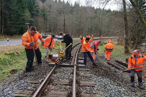 Die Schwellenschrauben werden mit Maschine angeschraubt und der Schotter wieder ins Gleisrost gegabelt.