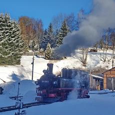 Knapp eine Stunde vor Abfahrt bewegt sich die Lok zum Vorheizen des Wagenzuges an den Bahnsteig, während die Sonne langsam über den Bergkamm steigt und den Lokschuppen bereits in Sonnenschein hüllt.