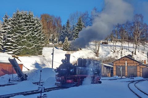 Knapp eine Stunde vor Abfahrt bewegt sich die Lok zum Vorheizen des Wagenzuges an den Bahnsteig, während die Sonne langsam über den Bergkamm steigt und den Lokschuppen bereits in Sonnenschein hüllt.