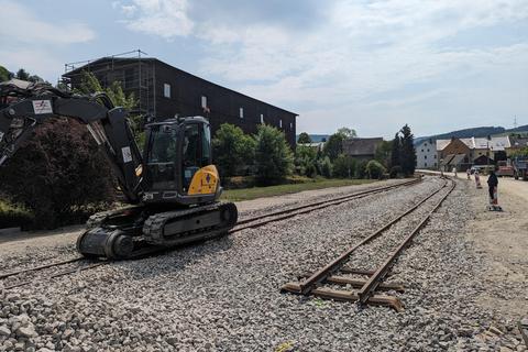 Ein Minibagger ist mit Schmalspurfahrwerk auf dem Gleis im Einsatz.