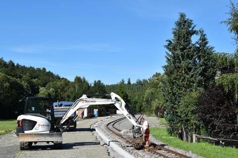 Mit dem Bagger wird der Schotter bis an den Bord aufgefüllt.